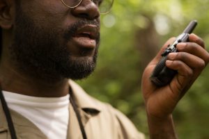Man pratar i en handhållen radio ute i en grön skog