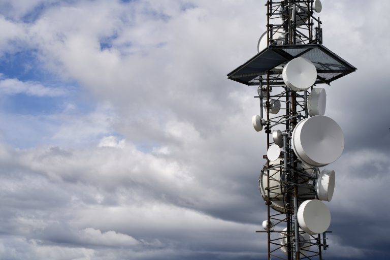 Mast med paraboler och antenner för radiolänkar mot en molnig himmel